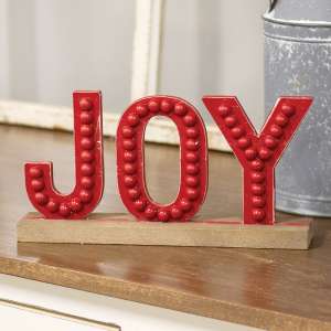 Bring a simple festive touch to any room this holiday with the Distressed Beaded Wooden Joy Sign on Base. The sign has an unpainted wood base holds the word 'JOY' in distressed red lettering with beaded details.